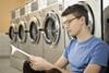 A photograph of a young man reading book in laundry