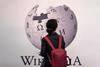 An image showing a woman standing in front of Wikipedia sign