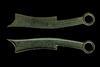 A pair of objects that look like stylised knives, and are about the same size. Their heavy patina suggests they are made from bronze.