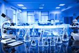 Close up of vials and beakers on a lab table with microscopes on each side