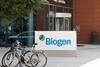 A sign saying Biogen with bikes locked nearby outside a modern office building