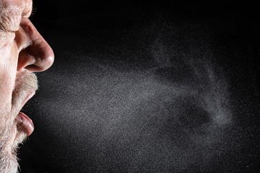 Close up of a man sneezing showing the droplets spreading from his nose and mouth