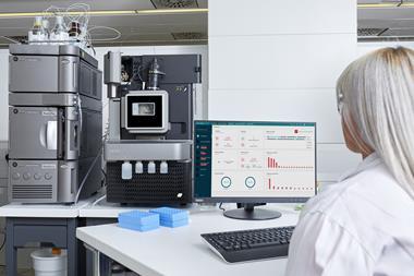 Scientist monitoring Waters Xevo TQ Absolute mass spectrometer and Acquity UPLC system with real-time data on a computer screen